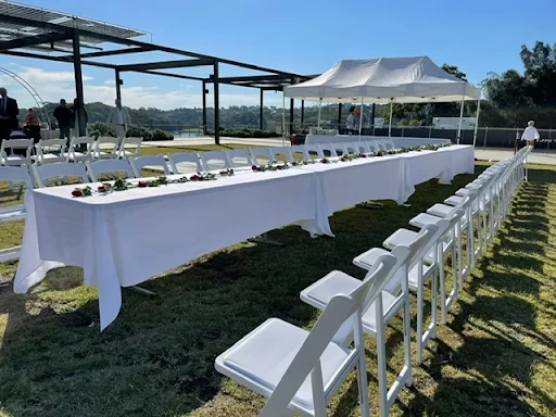An image of a large white table with multiple chairs.